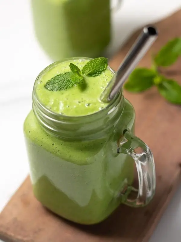 green keto smoothie in mason jar with silver straw