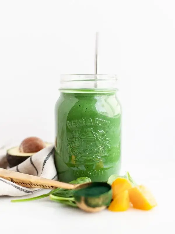 green spirulina smoothie in mason jar with ingredients
