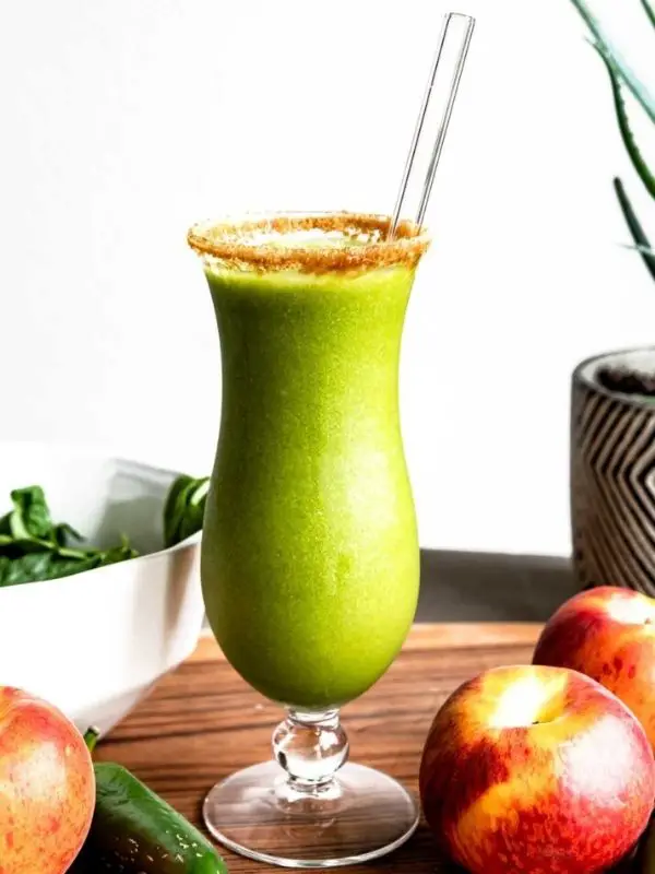 peach probiotic green smoothie in tall glass with fresh peaches