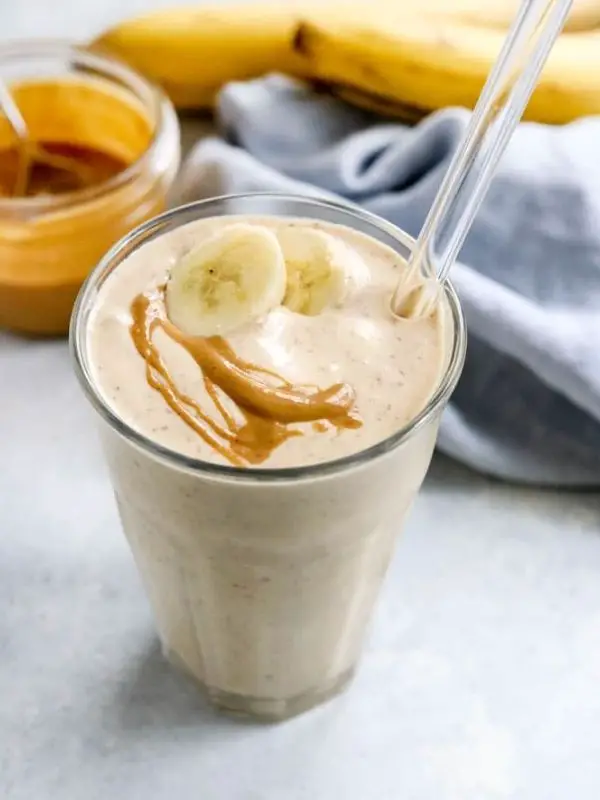 peanut butter and banana smoothie in a glass with fruit