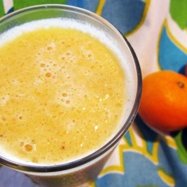 orange julius protein shake in tall glass with fresh orange